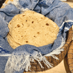 fresh milled flour tortillas in basket with blue towel.
