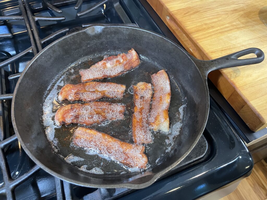 bacon cooking in cast iron skillet