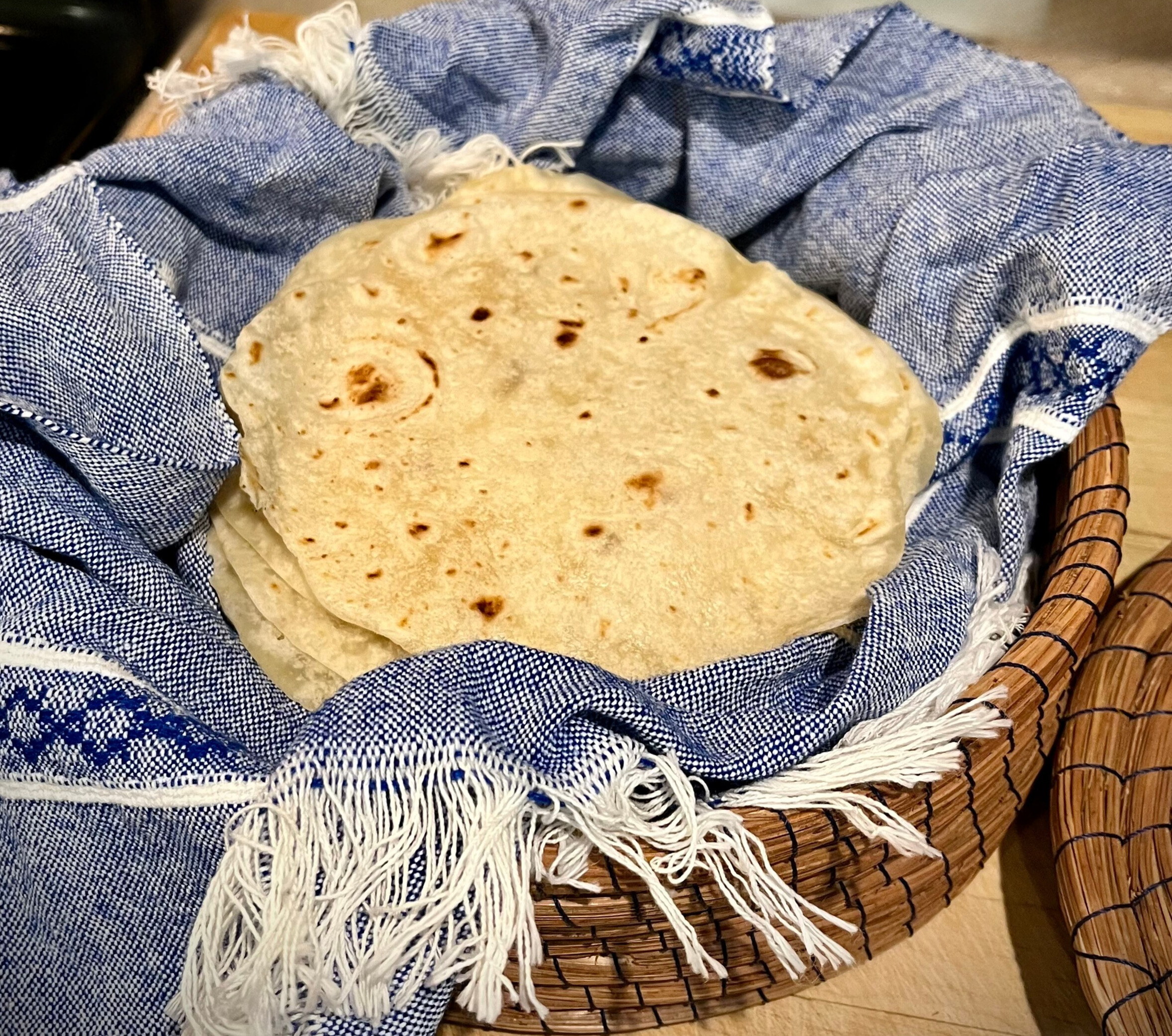 fresh milled flour tortillas in basket with blue towel