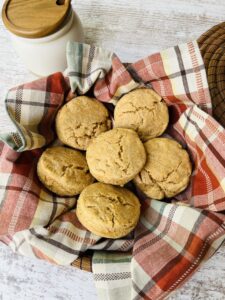 Biscuits made with fresh milled flour in plaid towel next to honey pot.