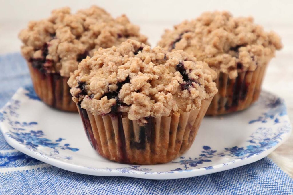 Fresh milled flour blueberry muffins topped with cinnamon streusel on a white plate
