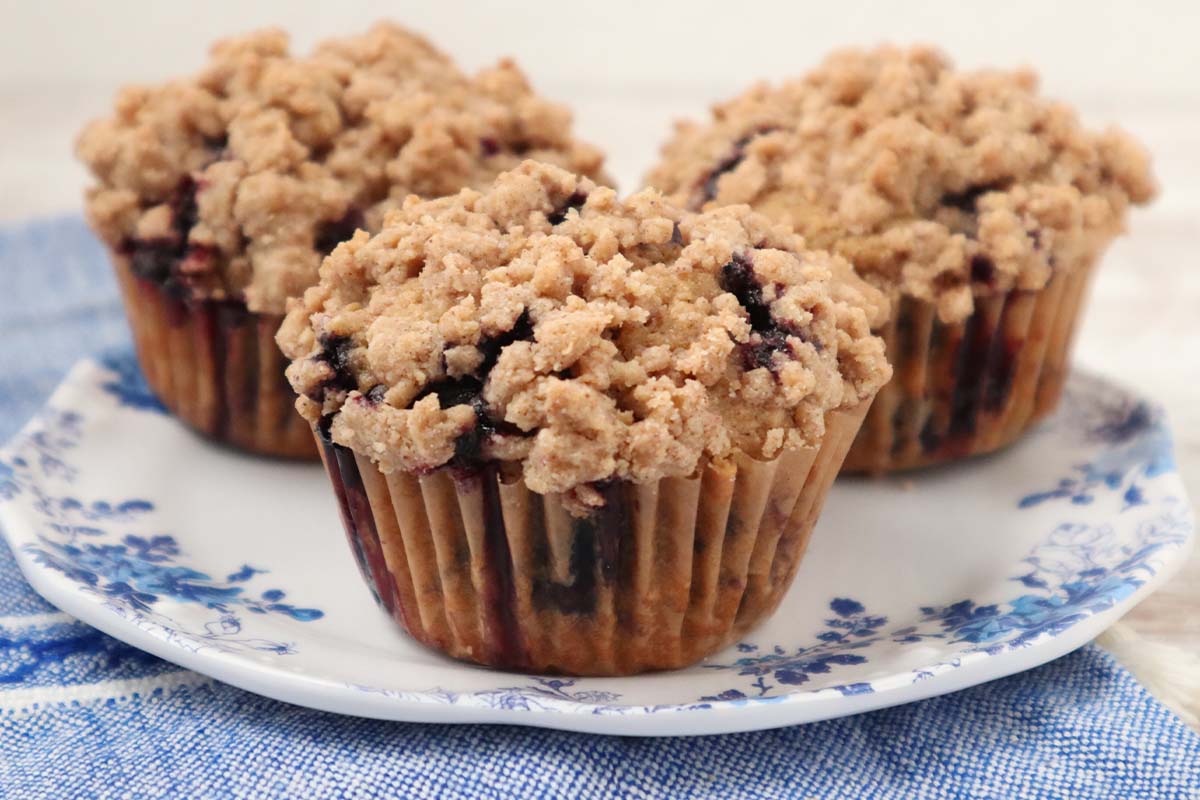 Fresh milled flour blueberry muffins topped with cinnamon streusel on a white plate