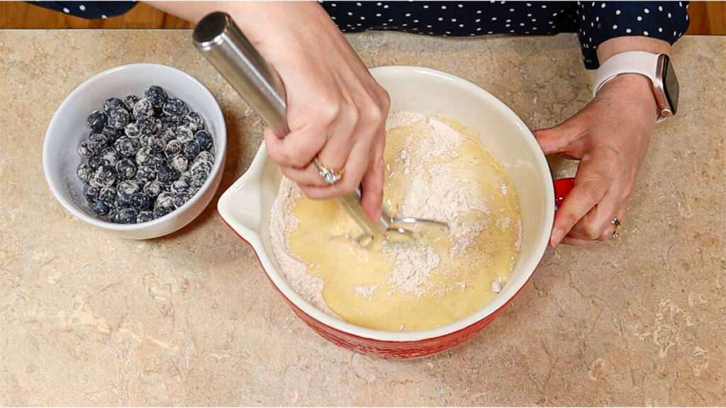 Mixing fresh milled flour blueberry muffin batter with blueberries nearby
