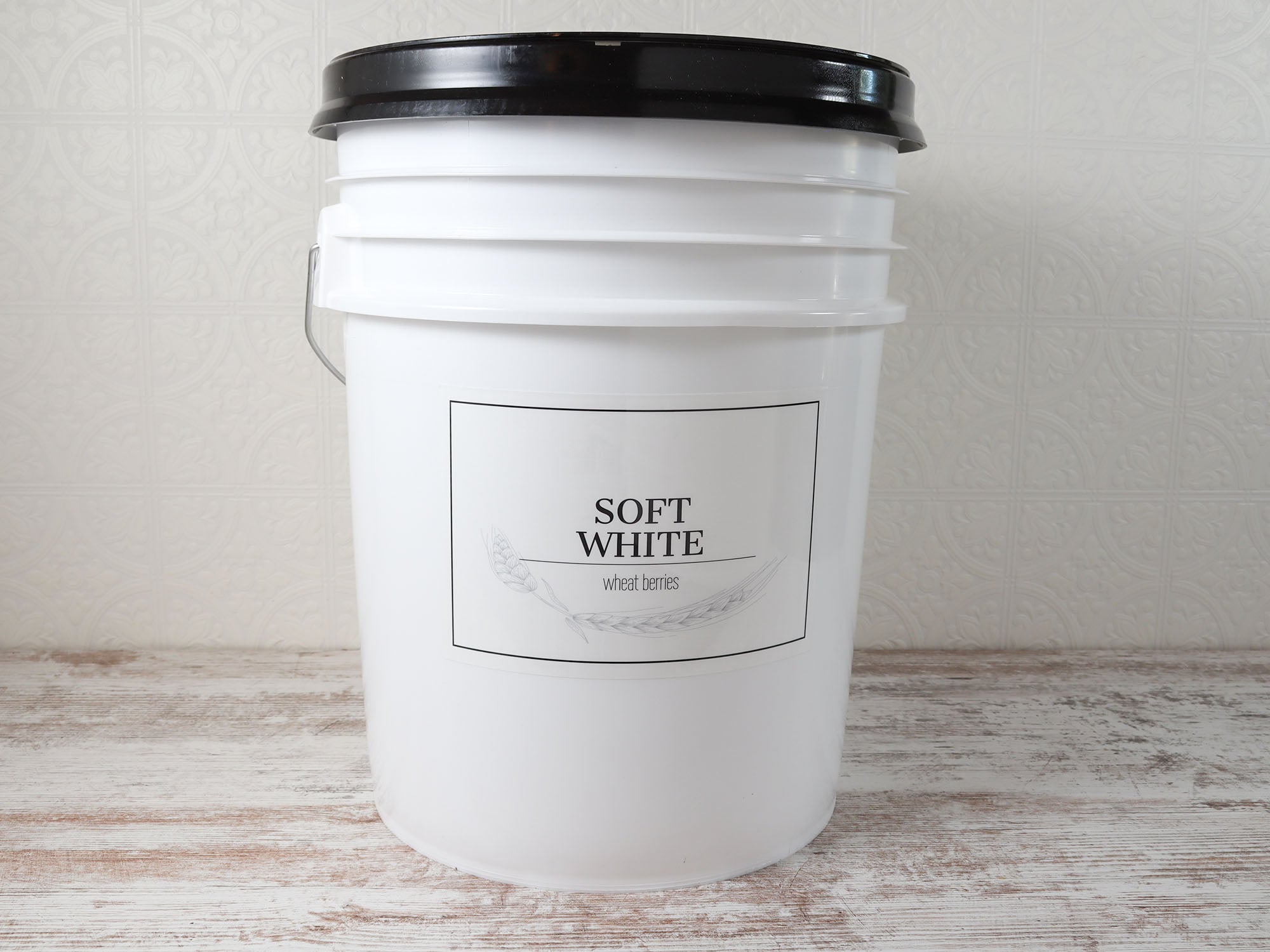 Large custom pantry label on a white wheat berry storage bucket, featuring a type-your-own-text design for soft white wheat berries.