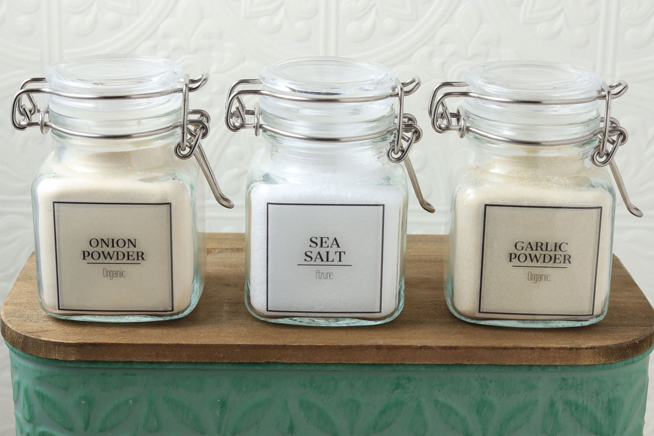 Type your own text pantry labels printed on clear sticker paper, shown on glass spice jars labeled onion powder, sea salt, and garlic powder.